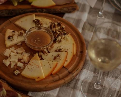 a plate of food with cheese and a glass of wine at Etno Garden Exclusive in Plitvička Jezera