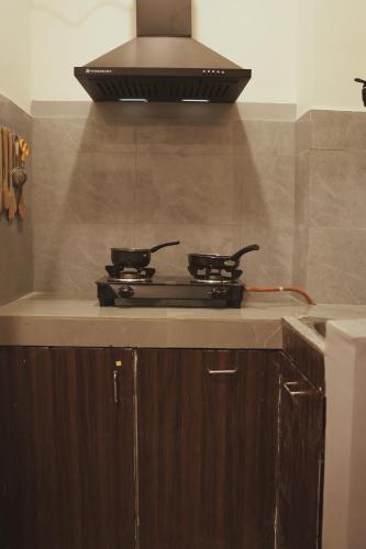 a stove top in a kitchen with a hood at The Guwahati Penthouse in Guwahati