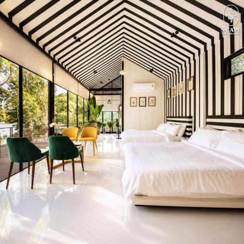 a bedroom with two beds and a table and chairs at S-Cape at Rim Khwae in Ban Tha Thong Mon