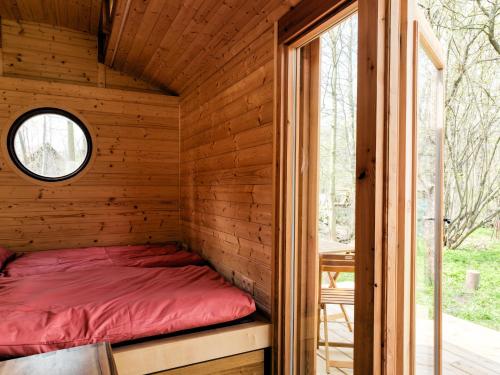 a bed in a wooden cabin with a window at Maringotka Bára in Huslenky