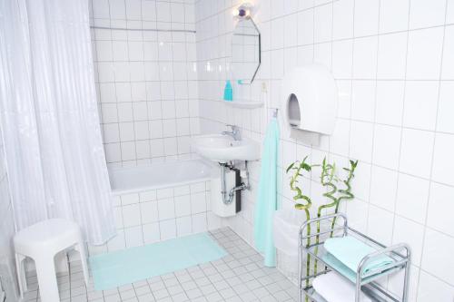 a white tiled bathroom with a sink and a toilet at Pension am Rathaus in Hamburg