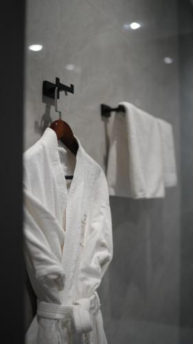 a white robe hanging on a rack in a bathroom at Diamond Hotel Shymkent in Shymkent