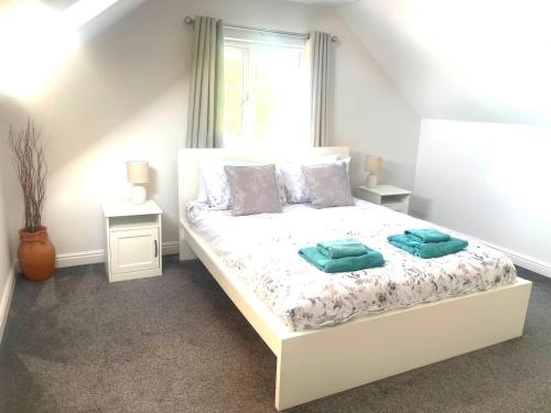 a bedroom with a white bed with two pillows on it at Spacious airy modern private detached house in Beeston