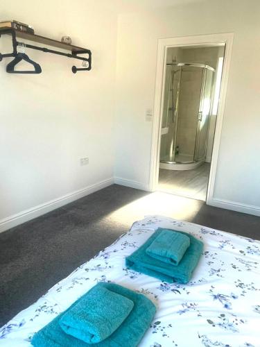 a bedroom with a bed with two towels on it at Spacious airy modern private detached house in Beeston