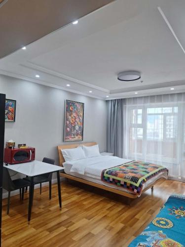 a bedroom with a bed and a table and a window at Undraa's cosy small apt in Ulaanbaatar