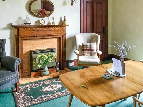 a living room with a table and a fireplace at Gladstone Cottage in Castletown