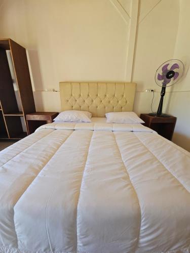 a large white bed in a room with a fan at Senaru Garden Homestay in Senaru