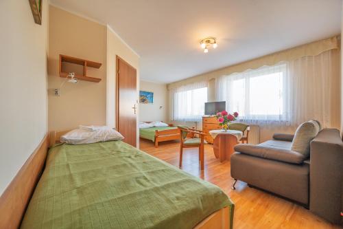 a living room with a bed and a couch and a chair at Bajka in Dąbki