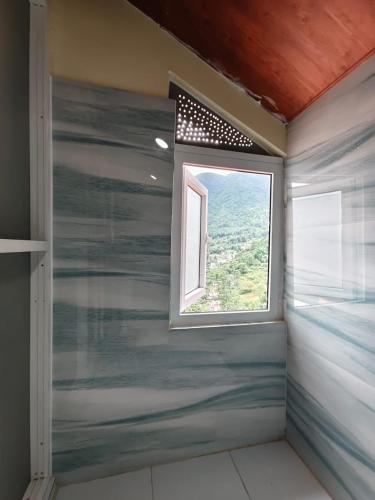 a shower with a window in a room at Penance Homestay in Khokna