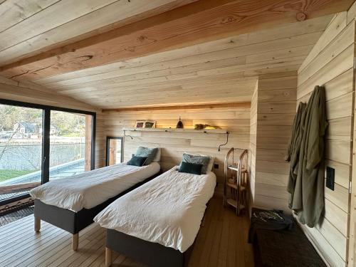 two beds in a room with wooden walls at O'Chambon in Chambon-sur-Lac