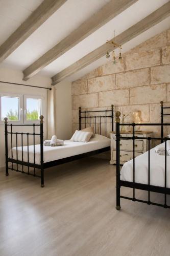 two black beds in a room with a stone wall at Cas Coco – 8-Person Townhouse near Playa de Muro ⭐ in Muro