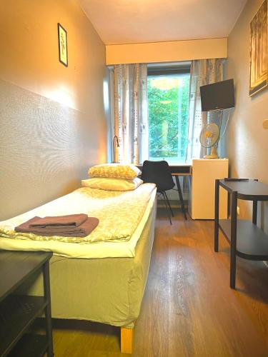 a bedroom with a bed and a desk with a window at Matkakoti Patria Hostel - single & double rooms in Lahti