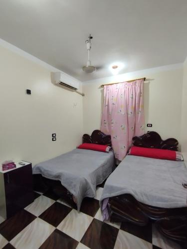 two beds in a room with a window at Couple's Cove in Luxor