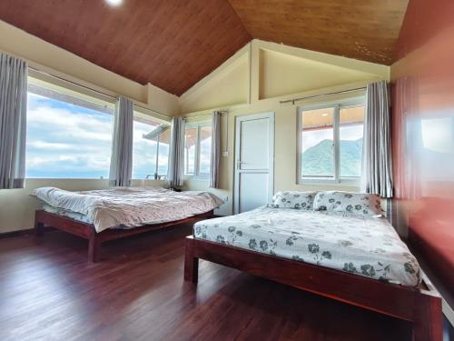 a bedroom with two beds and windows and wooden floors at Penance Homestay in Khokna