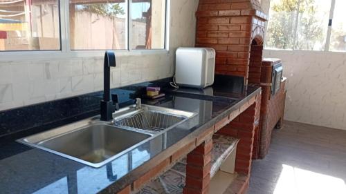 a kitchen with a sink and a brick wall at Chacara Mansao completa 28 pessoas TOMORROWLAND in Itu