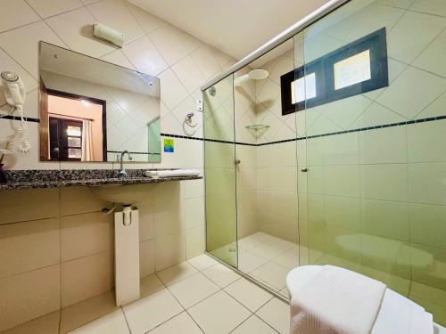 a bathroom with a glass shower and a sink at Hotel Enseada Maracajaú in Maracajaú