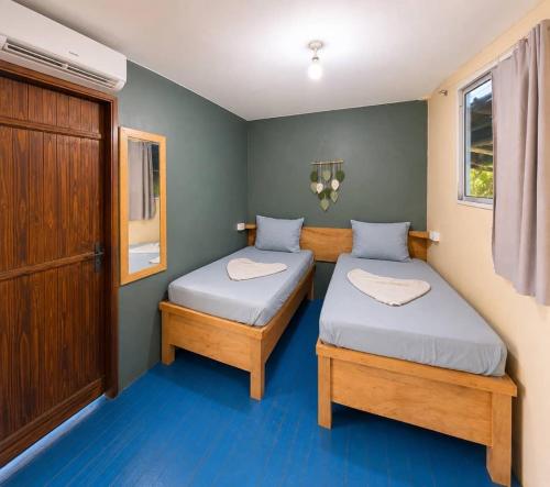 two twin beds in a small room with blue floors at Jambiani Backpackers Hostel in Jambiani