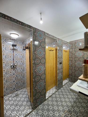 a bathroom with two wooden doors and a tiled wall at Ifni Flow Seafront surfhouse in Sidi Ifni