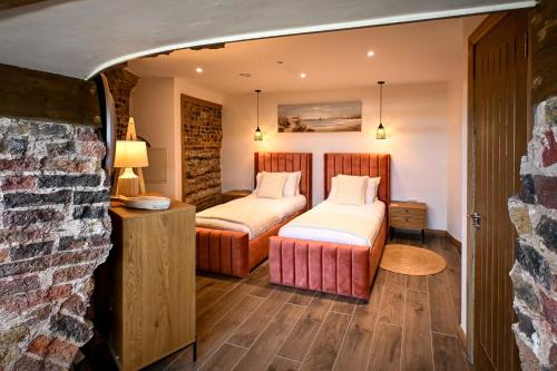 a room with two beds and a stone wall at Martello 25 in Dymchurch