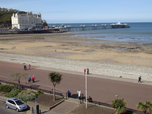 a view of a beach with a pier in the background at THE TREVONE, Llandudno in Llandudno