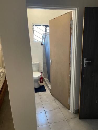 a bathroom with a toilet and a open door at Kokoma Apartment in Katima Mulilo in Katima Mulilo