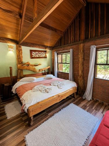 a bedroom with a bed in a room with wooden walls at Pousada Toque de Minas in Visconde De Maua