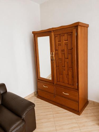 a wooden cabinet with a mirror next to a couch at Villa Daoura in Niamey