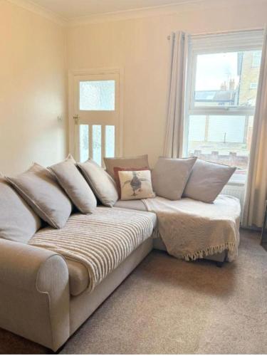 a couch with pillows on it in a room with a window at Walton Beach 1-Bed Cottage Sleeps 2 with Parking in Walton-on-the-Naze