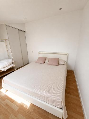 a white bed with two pink pillows in a room at Cosy T1 Bis climatisé in Toulouse