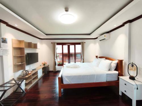 a bedroom with a white bed and a television at HR Resort in Ban Dong Bang