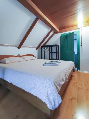 a bedroom with a large white bed with a green door at počitniška hiška MEDVEJKE in Slap ob Idrijci