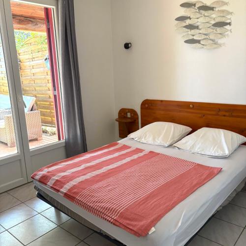 a bed with a red and white blanket and a window at auxcheneslieges in Lecci