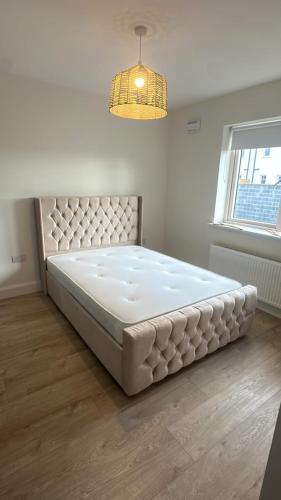 a large bed in a room with a window and a chandelier at The Comfort Corner in Dundalk