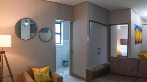 a living room with a couch and two mirrors at Apartment Next to Hotel in Pretoria