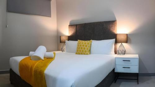 a bedroom with a large white bed and a nightstand at Apartment Next to Hotel in Pretoria