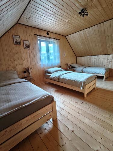 a bedroom with two beds in a wooden cabin at Relaks przy lesie in Idzbark
