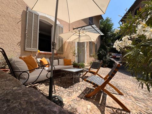 a patio with a couch and an umbrella and chairs at La Vicomtesse de Seillans in Seillans