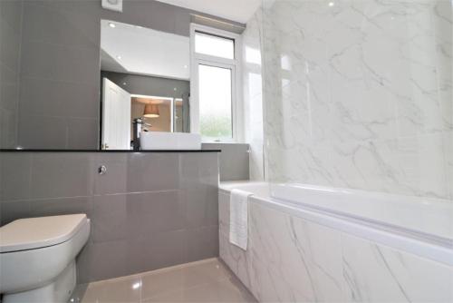 a bathroom with a tub and a toilet and a sink at Macintosh lower in Bellshill