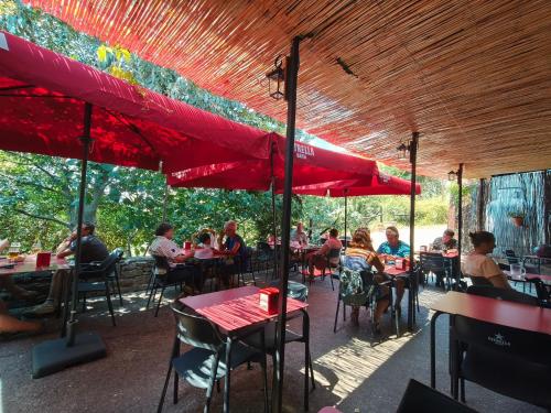 a group of people sitting at tables under a red umbrella at Albergue de Ruesta in Ruesta