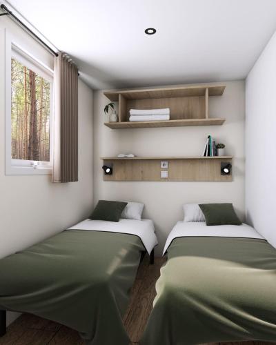 two beds in a room with a window at Camping Le Puits Rochais in Les Sables-d'Olonne