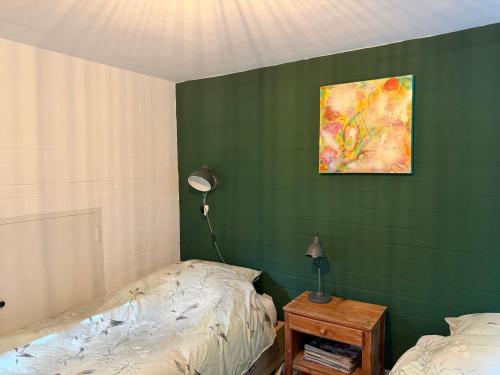 a bedroom with a green wall with a bed and a lamp at Suzie's Cottage in Aalten