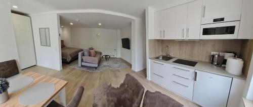 a kitchen with white cabinets and a table and a living room at Hotel Rebstock in Baden-Baden