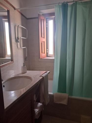 a bathroom with a sink and a green shower curtain at AQC - A Quinta Chama in Caldas da Rainha