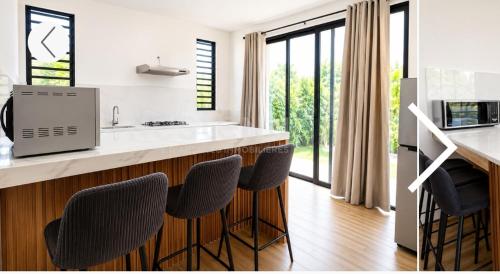 a kitchen with a counter with chairs and a counter top at Maranatha Villa in La Gaulette