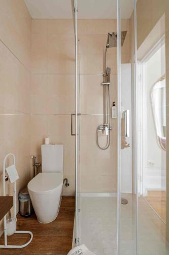 a bathroom with a toilet and a glass shower at Vestígios de Charme - Figueira Suits in Figueira da Foz