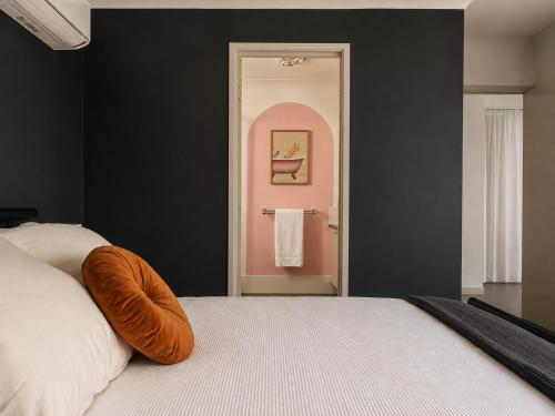 a bedroom with a white bed and a black wall at Layover Lounge in Perth