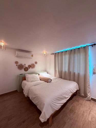 a bedroom with a bed with white sheets and a window at Star Fish Cozy House in Ban Nua
