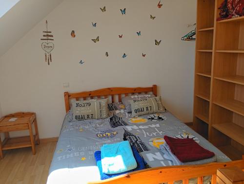 a bedroom with a bed with a blue comforter at La maison aux papillons in Tregueux