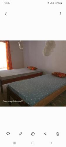 two beds in a room with avertisement for at J'adore House in Abémé
