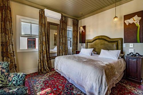 a bedroom with a bed and a chair and a mirror at Batavia Boutique Hotel in Stellenbosch